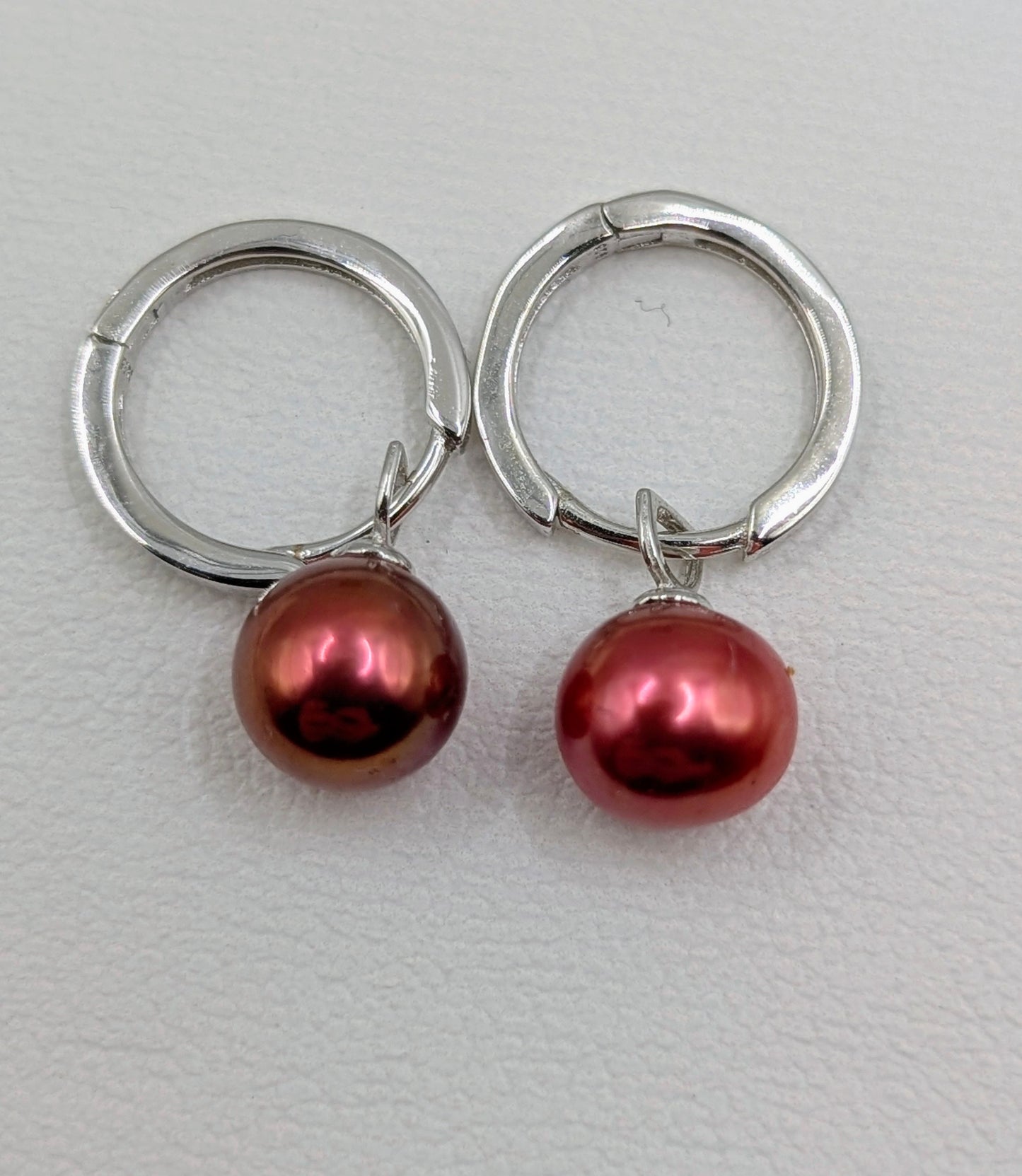 Sterling silver huggy earrings with metallic rose red pearl dangles.
